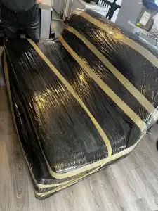 Professional mover wrapping a sofa with protective moving blankets